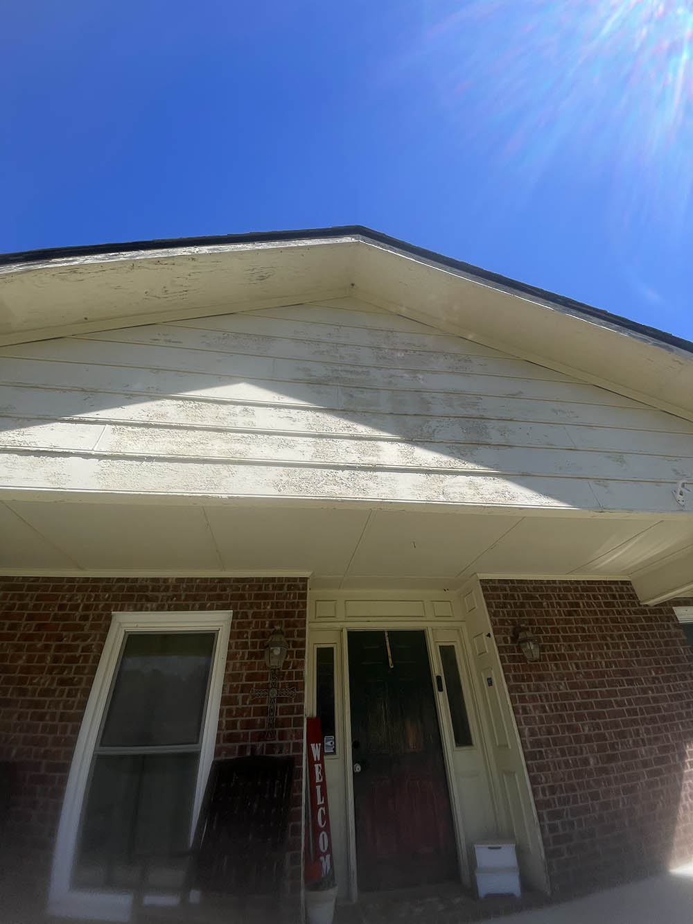 Weathered and heavily flaking gable siding on Eastover brick ranch home